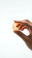 Woman's hand holding golden amber glass sphere against white background, isolated for design use on packaging, cosmetics, skincare, and luxury product marketing.
