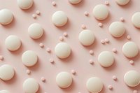 White macarons and small heart shapes creating geometric pattern on pastel pink background. Minimal food photography layout for bakery, wedding or Valentine's Day design.