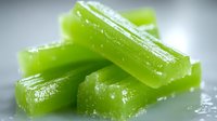 Fresh green celery sticks with water drops in macro view on light background, raw organic vegetable for healthy eating and cooking.