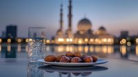 Dates and water glass on plate against illuminated mosque at dusk, bokeh lights reflecting on water surface creating peaceful Ramadan ambiance.