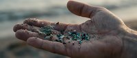 Hands holding colorful microplastic pollution particles from ocean water, environmental contamination and marine ecosystem damage concept.