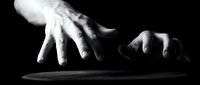 Dramatic black and white hands reaching toward each other in darkness, conveying connection, help, support and human emotion in artistic monochrome composition.