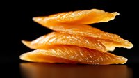 Fresh raw salmon slices stacked in layers on black background, showing delicate texture and natural orange color. Gourmet seafood preparation.