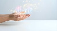 Caucasian male hand holding glowing holographic business charts and financial data visualization with floating light particles on white background for corporate analytics and digital technology concepts.