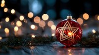 Red glass Christmas ball with star pattern on pine branches against blurred golden bokeh lights creating magical holiday atmosphere.
