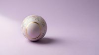 Elegant white ceramic sphere with golden floral patterns on soft purple background for luxury home decor and modern interior design concepts.