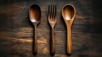 Wooden cutlery set with spoons and fork on dark rustic background with dramatic lighting, showcasing sustainable eco-friendly kitchen utensils for dining and food service.