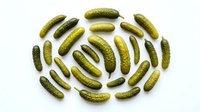 Pickled cucumbers arranged in circular pattern on white background, preserved vegetables for culinary and food design projects.