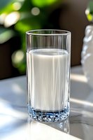Fresh glass of milk on marble surface with natural sunlight and bokeh background, casting soft shadows. Clean and minimalist food photography.