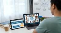 Asian woman participating in online education video conference call on laptop with diverse group of students learning remotely from home office workspace.