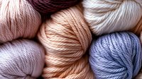 Soft pastel colored yarn skeins in pink, peach, lavender and blue tones arranged together for knitting and crochet crafting projects.