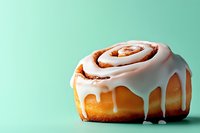 Freshly baked cinnamon roll with sweet white icing dripping down sides against mint green background, perfect for food marketing.