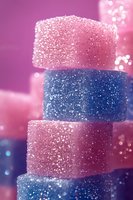 Stacked pink and blue glittery sugar cubes or decorative blocks creating magical contrast against blurred bokeh background, suitable for festive or celebration designs.