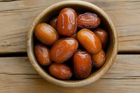 Fresh ripe dates in wooden bowl on rustic table background, healthy organic dried fruit snack for natural sweetness and nutrition.