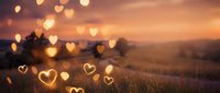 Romantic sunset landscape with golden heart-shaped bokeh lights over rolling hills and lavender fields creating dreamy atmosphere for love themes.
