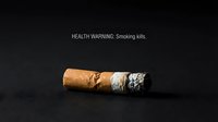 Cigarette butt with ash on dark background showing health warning message about smoking dangers and tobacco addiction consequences.