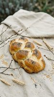 Fresh braided challah bread with poppy seeds on linen cloth with wheat stalks and willow branches for traditional baking and holiday celebrations.
