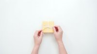 Hands opening small yellow gift box with red ribbon on white background, top view flat lay composition for special occasions and celebrations.