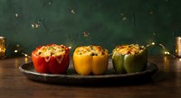 Colorful stuffed bell peppers with rice and herbs on rustic wooden table with warm lighting for cozy dinner presentation.