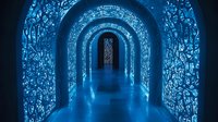 Mystical blue-lit corridor with illuminated arched passageway featuring intricate floral patterns on walls creating magical atmosphere for fantasy and architectural designs.