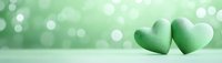 Two green hearts on soft bokeh background with romantic lighting for Valentine's Day, wedding invitations, love concepts and greeting card designs.