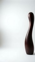 Elegant dark brown wooden club or baton standing upright against neutral background for design projects and creative applications.
