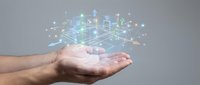 Hand holding glowing digital city hologram with connected buildings and network nodes, representing smart city technology, urban development, and IoT infrastructure solutions.