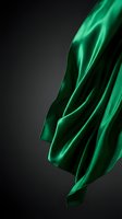 Luxurious emerald green silk fabric flowing gracefully against dark background creating elegant waves and folds for premium fashion and textile design.