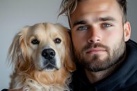 Young Caucasian man with beard and golden retriever dog posing together in close-up portrait showing bond between pet owner and companion animal.