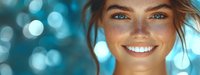 Young Caucasian woman with freckles and bright blue eyes smiling against blurred turquoise bokeh background, showing white teeth and natural beauty look.