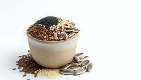 Ceramic bowl filled with assorted healthy seeds including sunflower, flax, chia and sesame on white background for nutrition concepts.