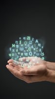 Hand holding glowing multilingual characters and education symbols against dark background, representing language learning, global communication, translation services, and international education for web and marketing use.