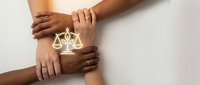 Diverse hands joined together with glowing scales of justice symbol, representing unity, legal support, teamwork in law, equality and fair treatment for business and community.