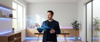 Young Caucasian businessman in dark suit presenting holographic interface technology in modern office with natural lighting and minimalist design.