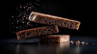Chocolate bars with cocoa powder explosion on dark background for confectionery and dessert advertising campaigns.