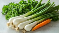 Fresh green onions with white bulbs, bright orange carrot and curly parsley arranged on light surface. Clean eating and healthy cooking ingredients.