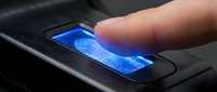 Finger touching biometric fingerprint scanner with blue glowing light on black device for secure authentication and identity verification technology.