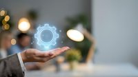 Business professional holding glowing gear icon representing automation, technology solutions, and digital transformation in modern office environment.