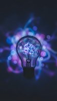 Glowing light bulb with electric filament against blurred bokeh lights background symbolizing innovation creativity and bright ideas for business concepts.