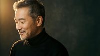 Mature Asian businessman in black suit smiling confidently with warm lighting, professional corporate portrait for business and leadership concepts.
