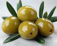 Fresh green olives with olive branch leaves arranged on white background for Mediterranean cuisine and healthy cooking recipes.