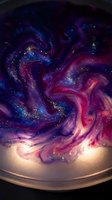 Swirling galaxy-inspired glitter paint mix in purple, blue and pink tones with sparkling particles, cosmic abstract art background.