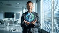 Professional businessman in suit holding glowing green sustainability symbol in modern office environment representing corporate environmental responsibility.