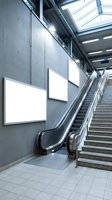 Modern subway station with blank illuminated advertising displays on concrete wall next to escalator and stairs, ideal for transit advertising mockups and commercial signage concepts.