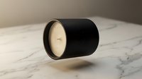 Elegant black cylindrical candle with cream wax on marble surface. Minimalist home decor accessory for relaxation and ambient lighting in modern interiors.