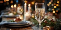Sparkling champagne glass on elegant holiday table with festive bokeh lights, candles, and seasonal decorations for celebration.