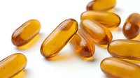Amber-colored gel capsules and supplement pills scattered on white background for health and wellness product photography.