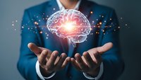 Professional businessman in blue suit holding glowing digital brain hologram with light effects representing artificial intelligence and innovation.
