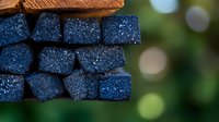 Stacked blue glittery foam cubes create geometric pattern against blurred natural background, adding sparkle and texture for creative design projects and decorative use.