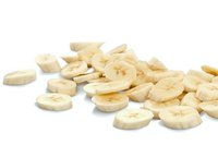 Fresh sliced banana pieces scattered on white background, ripe yellow fruit cut in round shapes showing natural texture and pattern, isolated for food design.